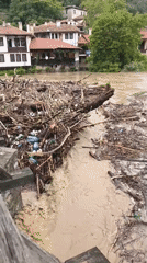 Swollen debris-filled river flows rapidly through Veliko Tarnovo, Bulgaria