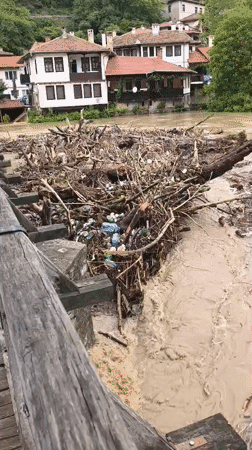 Swollen debris-filled river flows rapidly through Veliko Tarnovo, Bulgaria