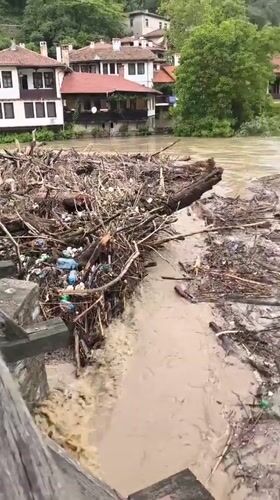 Swollen debris-filled river flows rapidly through Veliko Tarnovo, Bulgaria