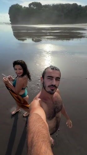 Couple documents beach visit on black sand in Selemadeg