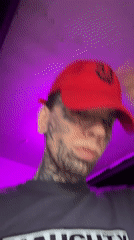 Close-up portrait: heavy facial tattoos, red cap, Buenos Aires