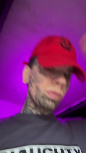 Close-up portrait: heavy facial tattoos, red cap, Buenos Aires