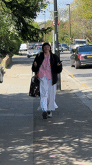 Woman in checkered shirt walks London sidewalk Saturday morning