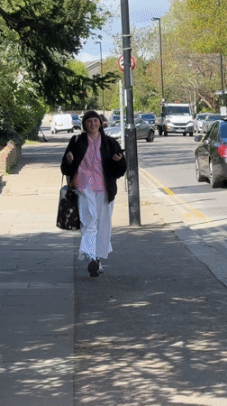 Woman in checkered shirt walks London sidewalk Saturday morning