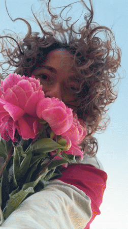 Person enjoys pink peonies in Noviy, Russia