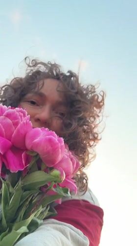 Person enjoys pink peonies in Noviy, Russia