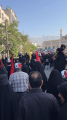Black-clad procession moves through Tehran streets carrying flags