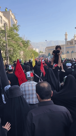 Black-clad procession moves through Tehran streets carrying flags