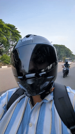 Motorcyclist observed on tree-lined street in Dhaka