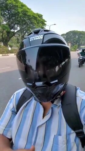 Motorcyclist observed on tree-lined street in Dhaka