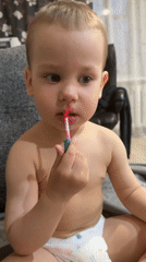 Toddler applies pink lip gloss in Rusanovo, Russia