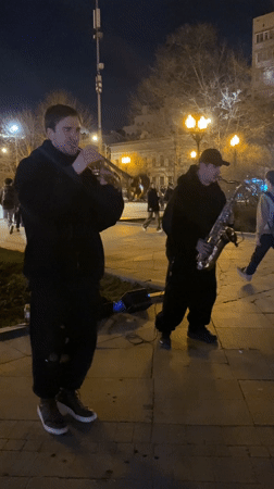 Two musicians perform trumpet and saxophone outdoors in Moscow