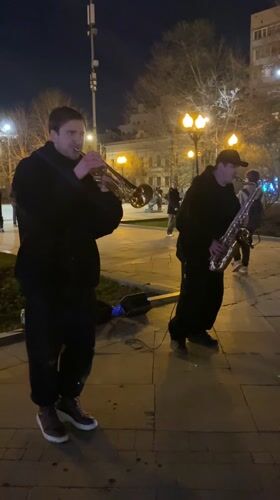 Two musicians perform trumpet and saxophone outdoors in Moscow