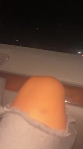 The video shows a close-up of a person's knee and thigh. The person is wearing ripped gray jeans. The background is dark, suggesting it is nighttime. The interior of a car is visible, including a dashboard with a radio and air vents, and a wooden trim. There is a car air freshener hanging from the rearview mirror.