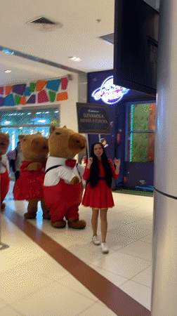 Woman poses with capybara mascots in Peru shopping mall
