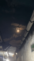 Full moon with orange glow observed through clouds in Madiun