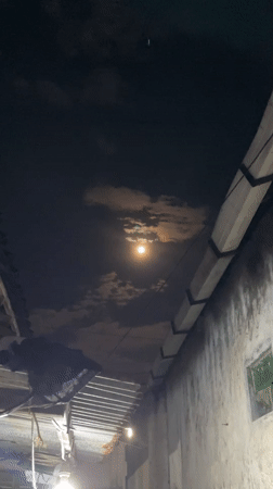 Full moon with orange glow observed through clouds in Madiun