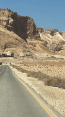 Driving through arid desert terrain toward distant buildings in southern Israel