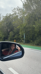 Passenger makes peace sign in car mirror reflection