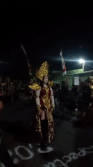 Ceremonial costume and light show at a nighttime street event in Tebel