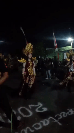 Ceremonial costume and light show at a nighttime street event in Tebel