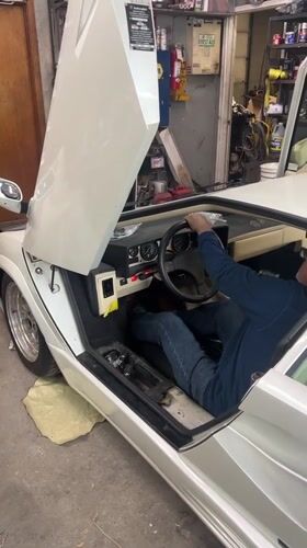Men work on white Lamborghini in Waterbury garage