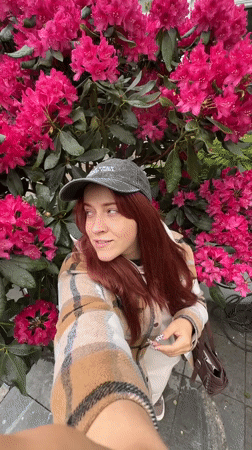 Woman photographs blooming rhododendrons during afternoon rain shower