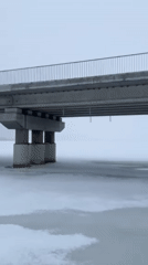 Person walks toward damaged bridge in snowy Staryi Saltiv