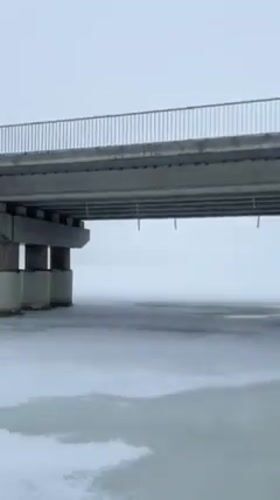 Person walks toward damaged bridge in snowy Staryi Saltiv
