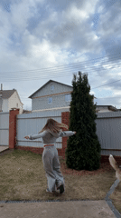 Woman plays with dog in backyard during early morning hours