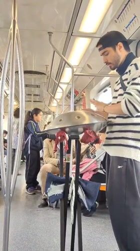 Street musician plays handpan drum for subway passengers in Chile