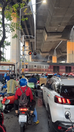 Train crosses Bangkok street as traffic waits below overpass