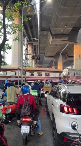 Train crosses Bangkok street as traffic waits below overpass