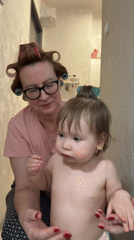 Woman in hair rollers plays with baby at Moscow home