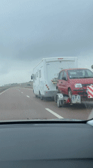 Motorhome tows red car on trailer along Moroccan highway
