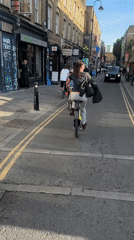 Cyclists including paint-splattered woman ride through busy London street