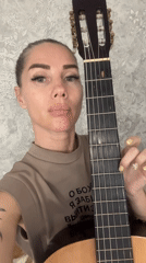 Woman plays classical guitar in casual indoor session, Abakan