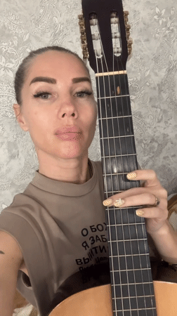 Woman plays classical guitar in casual indoor session, Abakan