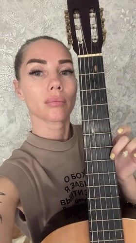 Woman plays classical guitar in casual indoor session, Abakan