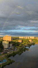 Rainbow appears over city during cloudy afternoon conditions