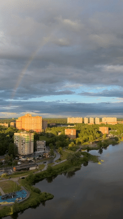 Rainbow appears over city during cloudy afternoon conditions