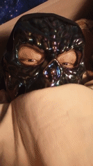 Person wears iridescent skull mask in bed, mask photographed