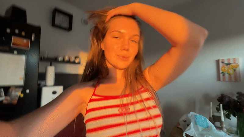 Woman dances in Belgrade kitchen, sparkling water nearby