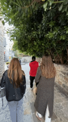 Pedestrians walk tree-covered stone pathway in Budva, Montenegro