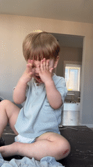 Toddler plays peek-a-boo during casual indoor moment in Russia
