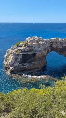 Natural rock arch frames turquoise sea on Mallorca's coast