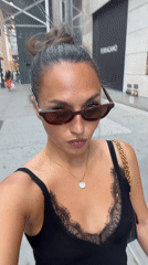 Woman in black dress walks NYC sidewalk Sunday evening