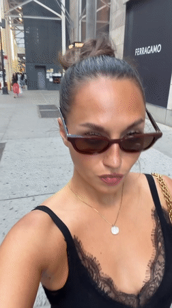 Woman in black dress walks NYC sidewalk Sunday evening