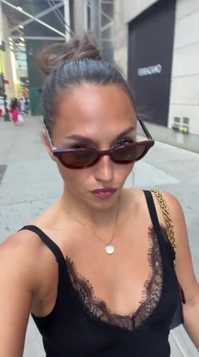 Woman in black dress walks NYC sidewalk Sunday evening