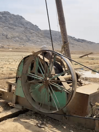Drilling operation observed in rural Afghanistan, workers rest nearby